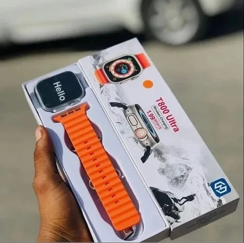 Hand holding a T800 Ultra smartwatch box showing a black watch with orange strap and Hello screen.